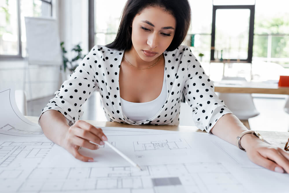 A woman checking a chart on a desk. Check out these 11 quick job certifications that pay well.