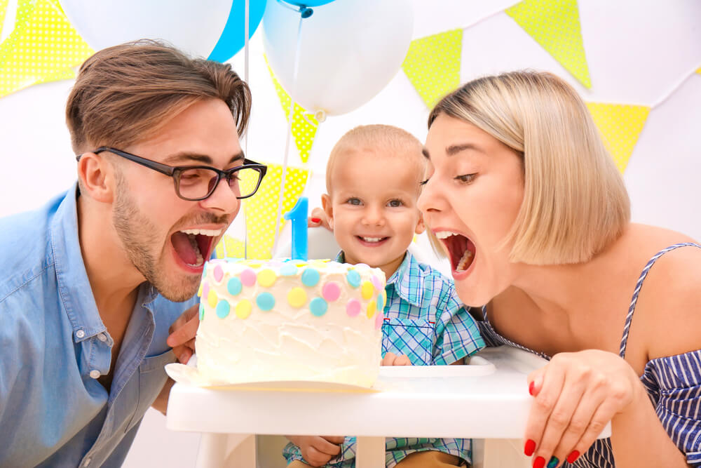 A man and a woman bowing a cake with a baby in their center, smiling. Learn more about 31 co-parenting tips to make shared custody a success.