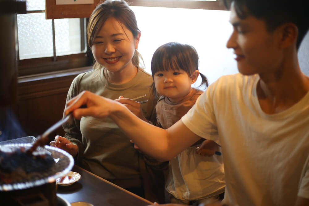 A family in the kitchen, the man cooking while the woman and kid are watching. These are 31 co-parenting tips to make shared custody a success. Check them out.