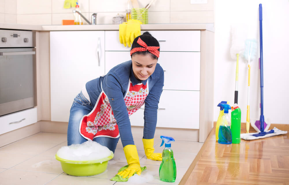 A woman cleaning the floor. You can try these 6 places to find a babysitter in 2024.