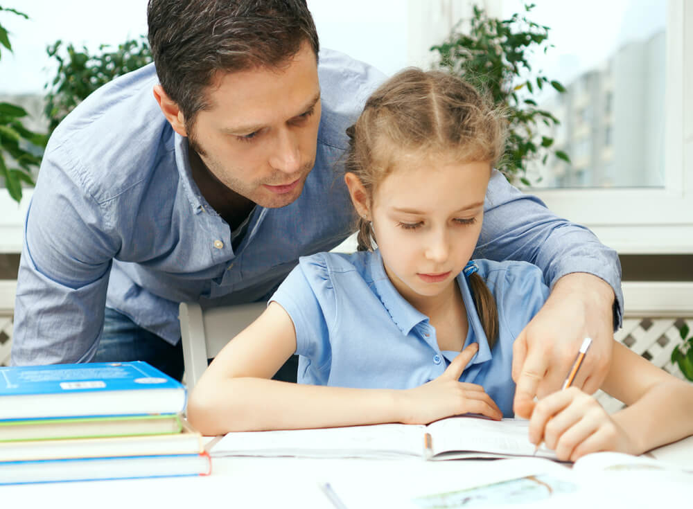 A man helping a child with her homework. Check out these 7 benefits of parenting classes and where to find them.