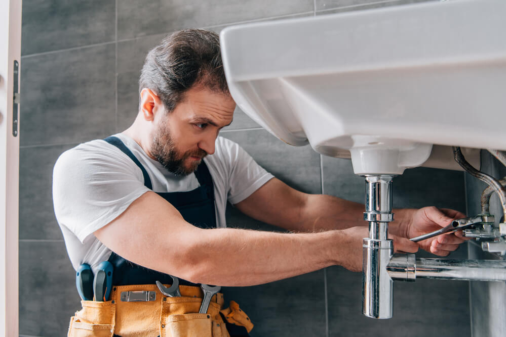 A plumber fixes a sink. Home service businesses are considered fairly recession-proof.