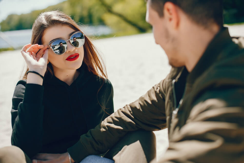 A woman in shades and corporate attire talks to a man driving a motorcycle. Here are 7 things you need to know before dating a man with kids in 2024. You can check them.