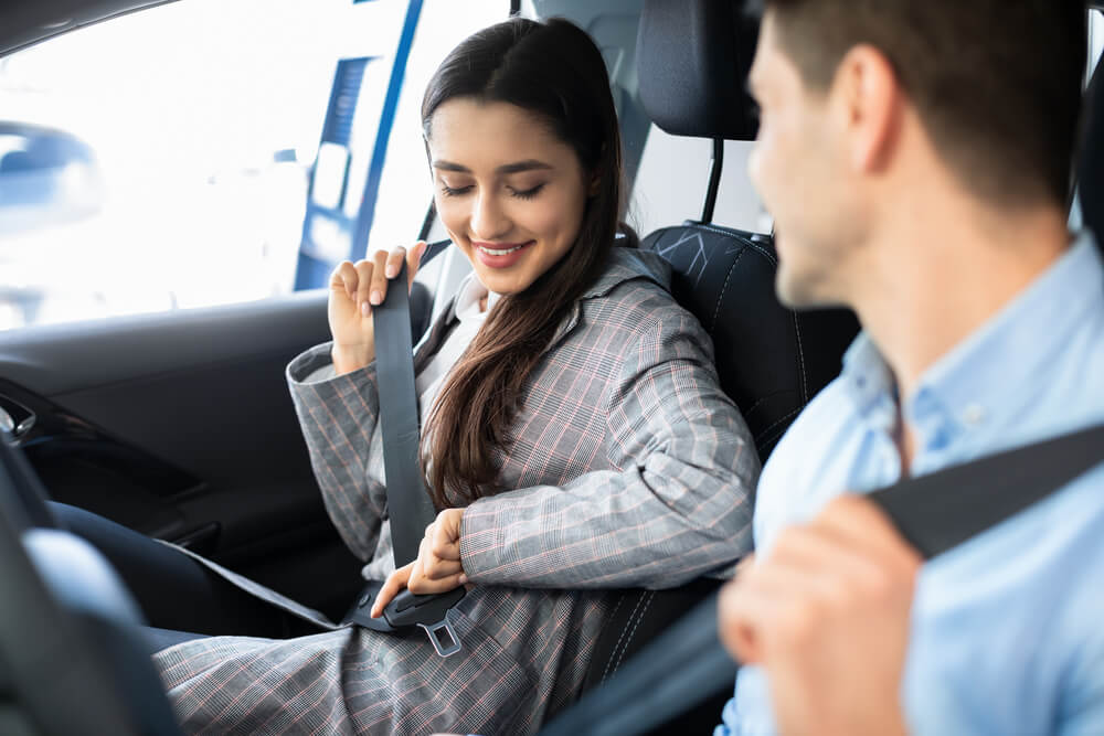A man and a woman buckling up inside a car. Free car insurance? Sorry. But there are ways to lower your premiums. Check them here.