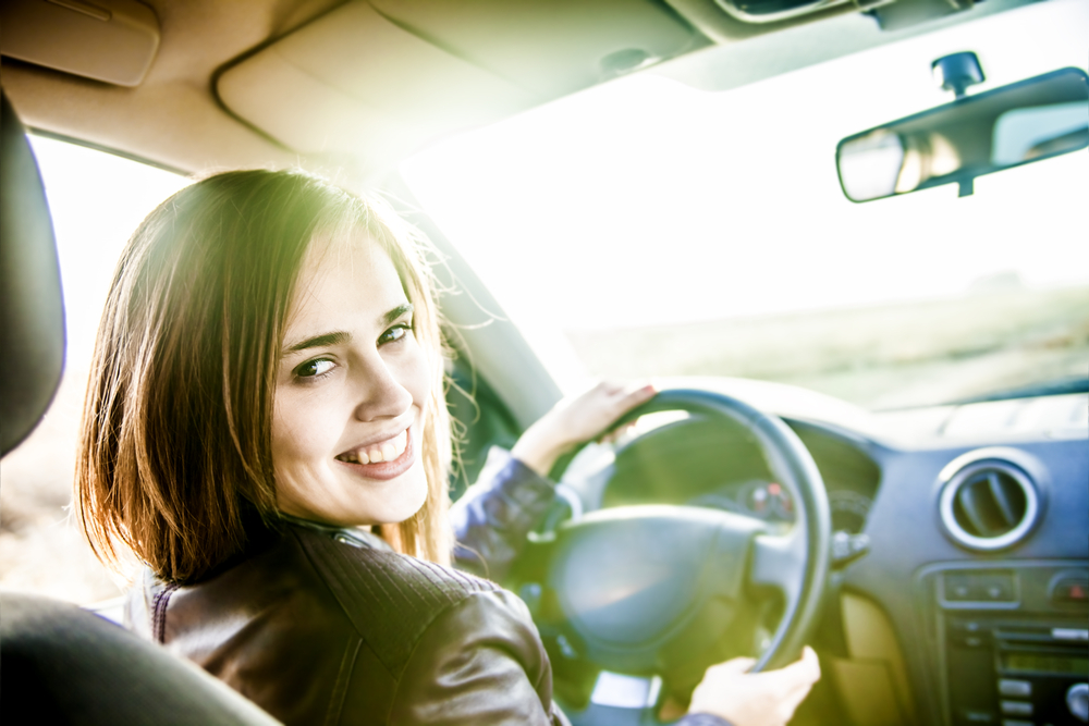 Young woman happy behind the wheel of her car - for cars for free