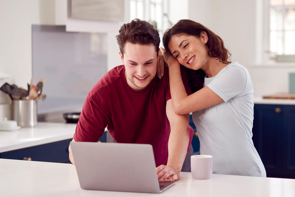 A couple looking at a laptop screen, smiling. Need money now? 15 ways to get free money instantly. Check them here.