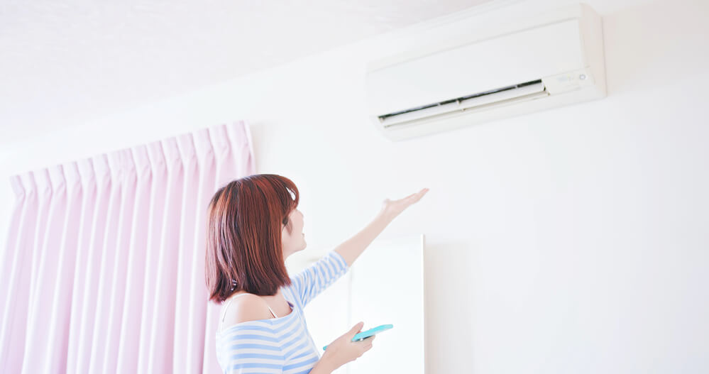 Woman checks if air is coming out of her air conditioner. Learn how you can qualify for a free air conditioner.