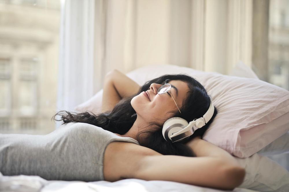 woman laying in bed listening to her free audiobook