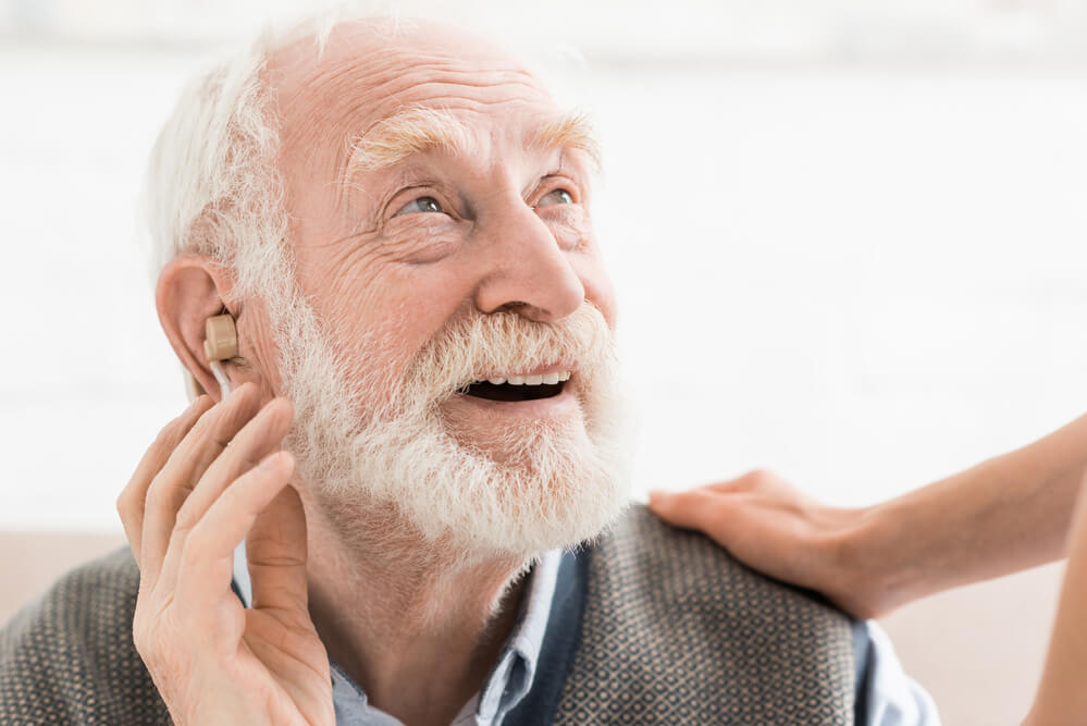 Senior man tries on free hearing aids. 