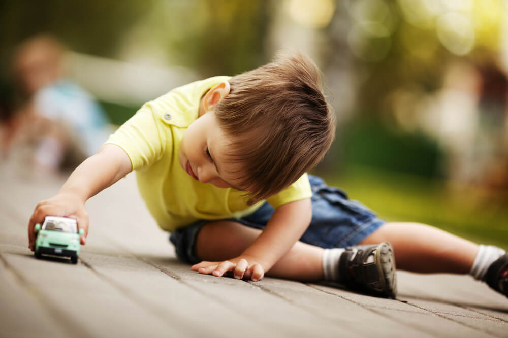 A little boy plays with a toy car. Check out 11 easy ways to get free toys for kids.