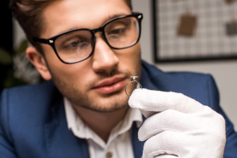 A man inspecting a ring. Check here for a guide to selling jewelry for cash (+ negotiation tips).