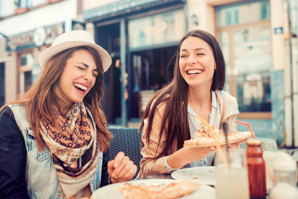 Two friends laugh over pizza. Hanging out is one way to comfort someone who is hurting.