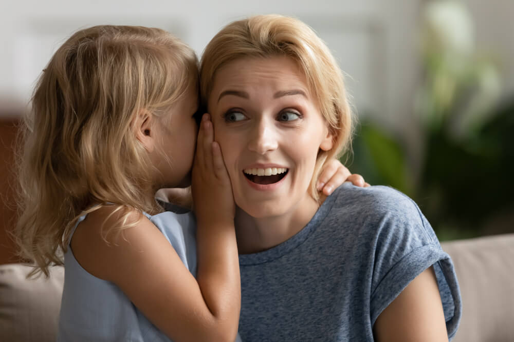 A baby whispering into a woman's ear. Learn how to find a nanny: try these 9 overlooked places to find a good nanny.