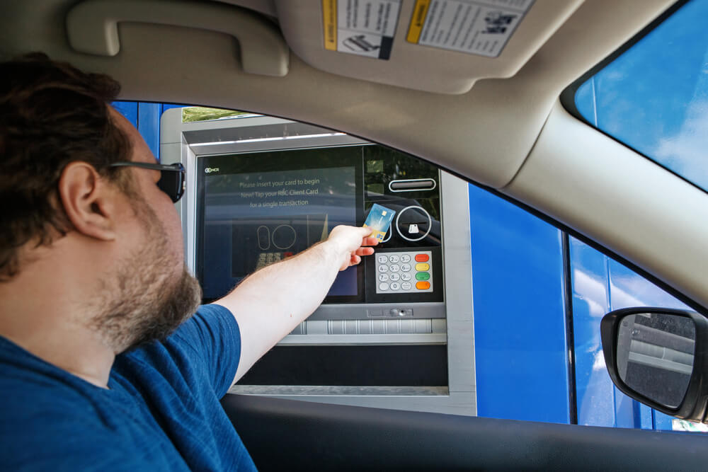 A man inside a car reaching out to pay using his card. Find out how to get free gas and discount gas in 2024: 8 legit ways.
