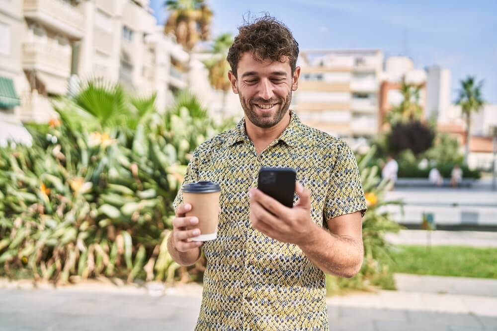 A man holding a mobile phone and smiling. Is my boyfriend cheating? 5 cheating apps and 11 signs to look for. Check them out.