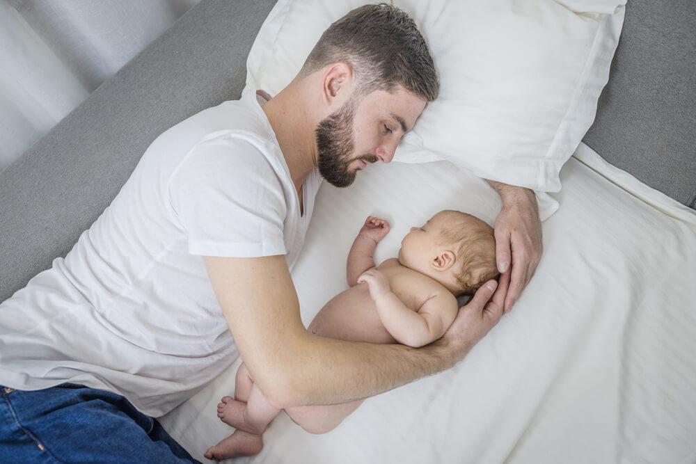 Single dad co-sleeping with newborn baby.