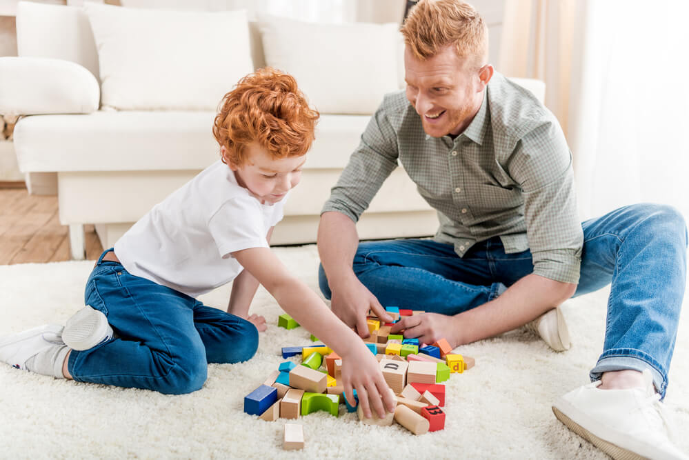 A dad and son play with blocks. Here are 11 easy ways to get free toys for kids.